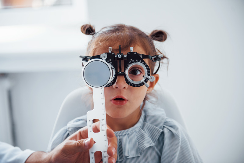 Little girl in eyewear in ophthalmology clinic have test of vision.